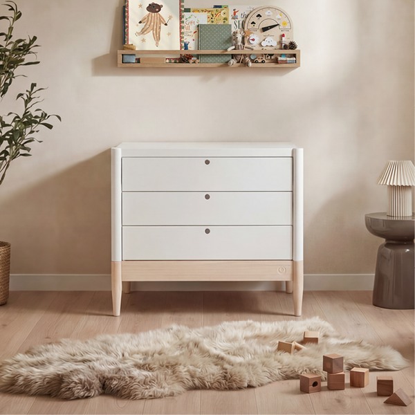 White Gaia Baby Eos dresser with natural wood accents, featuring multiple drawers for organized nursery storage.