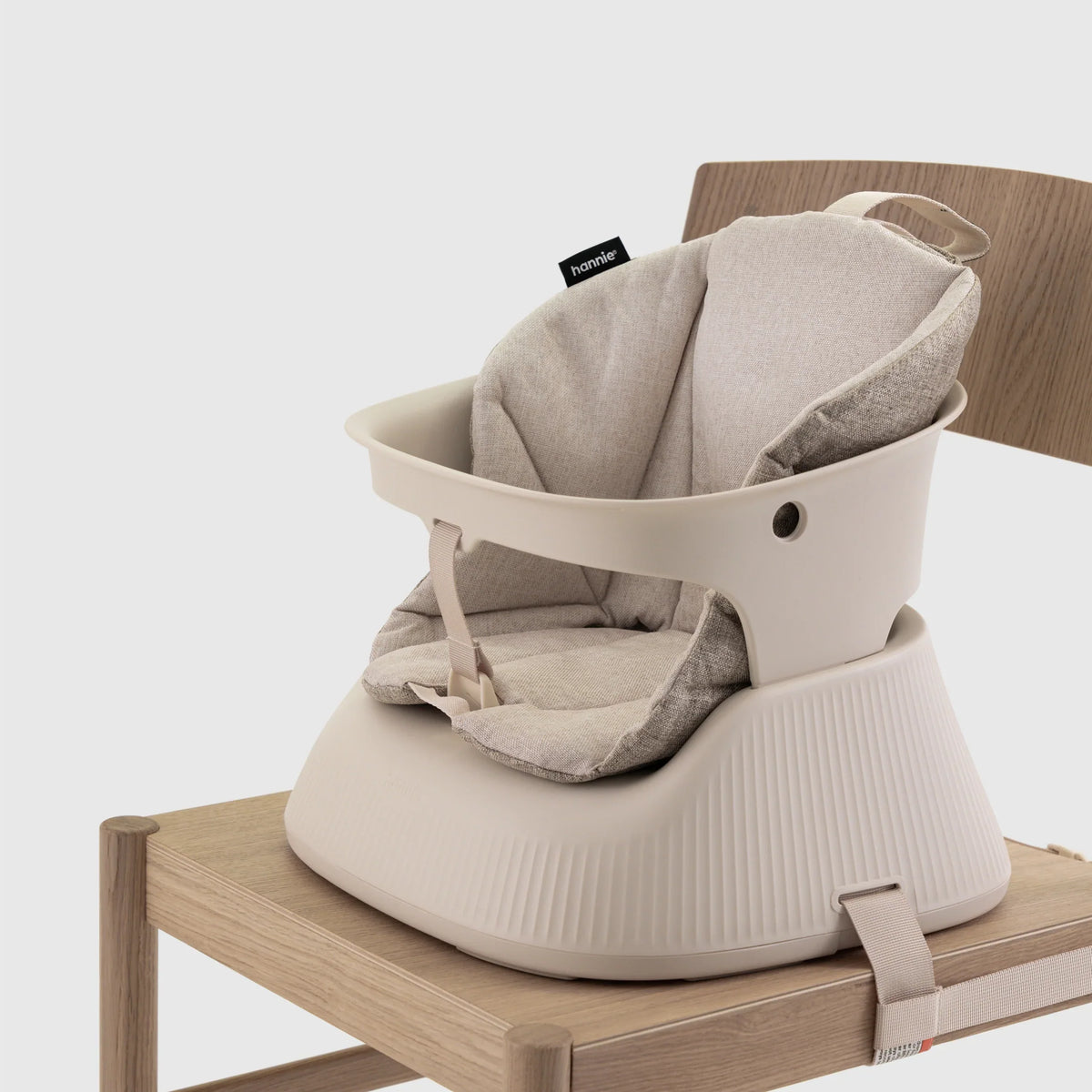 Hannie portable high chair in White Sand color with a sturdy frame and comfortable seat for infants and toddlers.