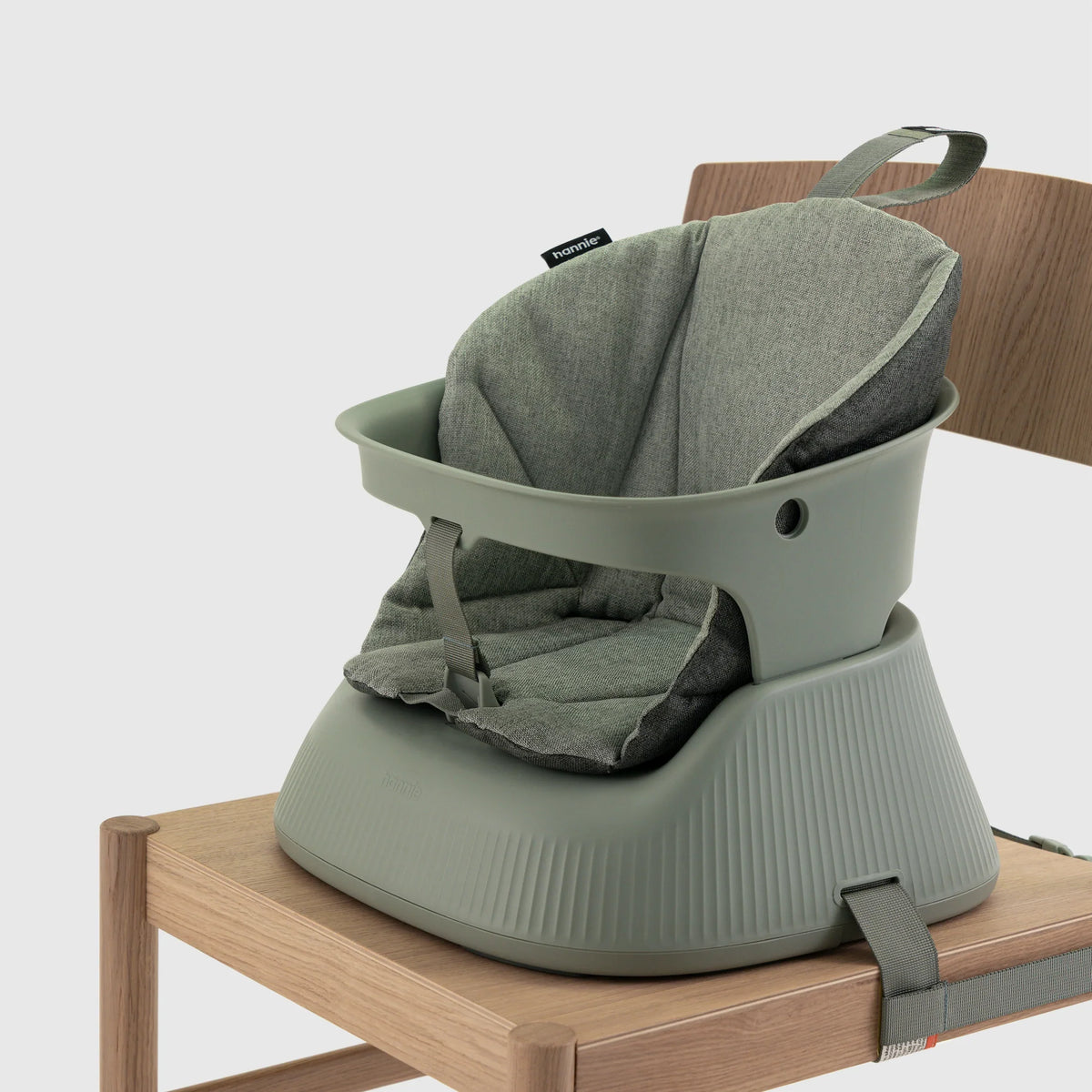 Hannie portable high chair in sage green with cushioned seat, designed for comfort and convenience, shown from a side perspective.