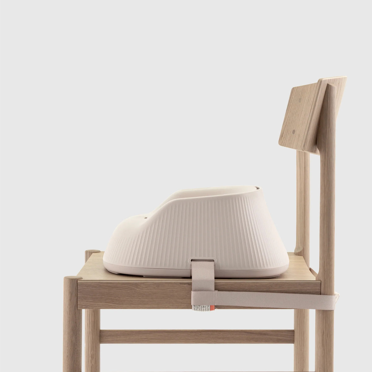Hannie portable high chair in white sand color, showing side view with seat and adjustable tray for convenient feeding.