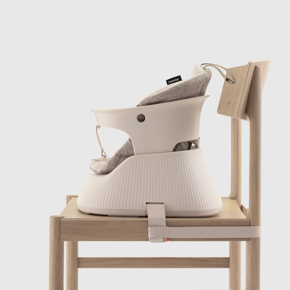 Hannie portable high chair in White Sand color, side view showing sturdy frame and comfortable seat for infants or toddlers.