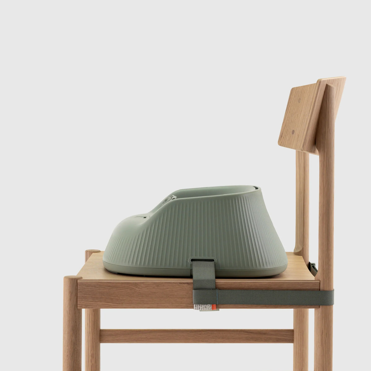 Hannie portable high chair in sage green, showing side view with adjustable seat and safety straps for babies and toddlers.
