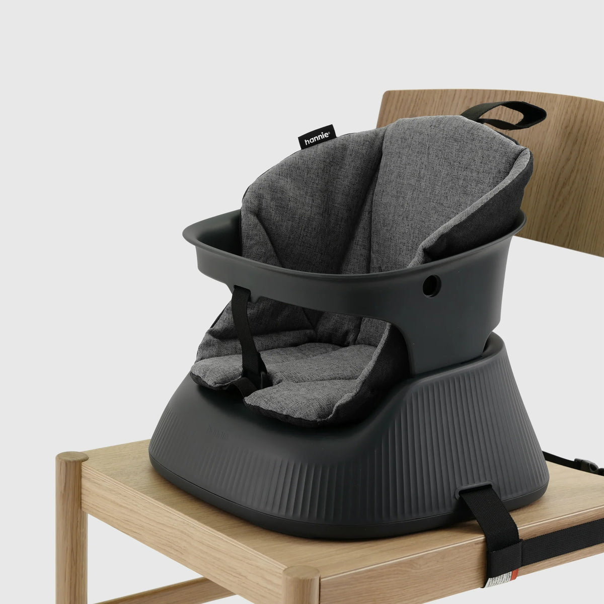 Hannie portable high chair in charcoal black, shown from a perspective view with a sturdy wooden tray and compact design.