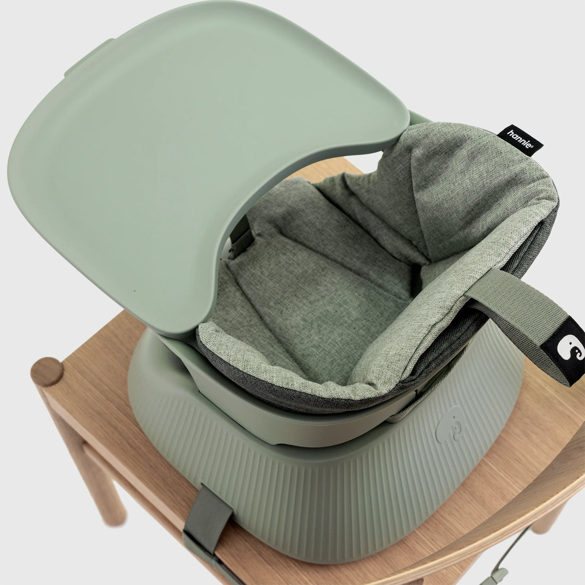 Hannie portable high chair in sage green with adjustable tray and safety straps, suitable for infants and toddlers.