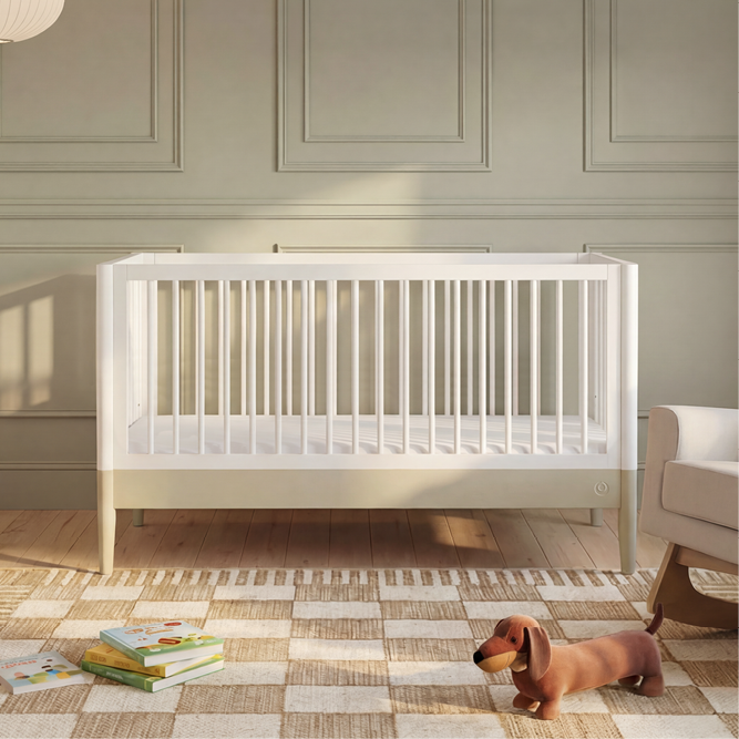 White Gaia Baby Eos Cot Bed with Desert Sage accents, featuring a sturdy wooden frame and slatted sides for safe sleep.