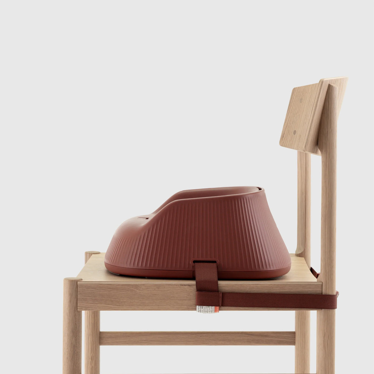 Hannie portable high chair in mahogany red, shown from the side with a sturdy seat and adjustable features for easy seating.