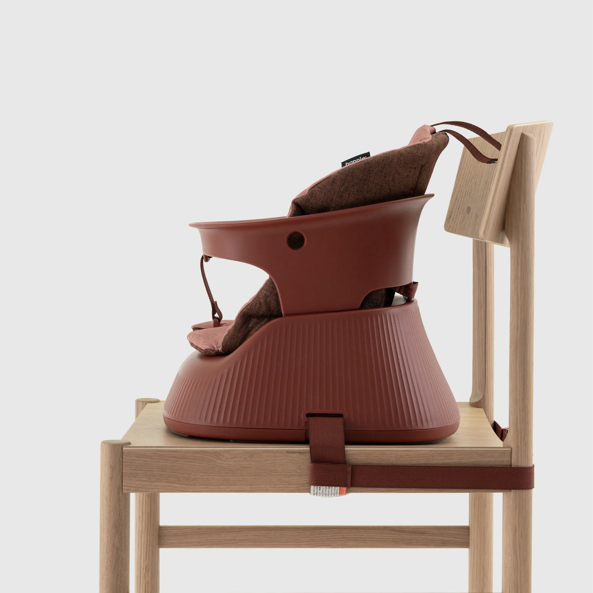 Hannie portable high chair in mahogany red with a cushioned seat, side view showing sturdy wooden frame and compact design