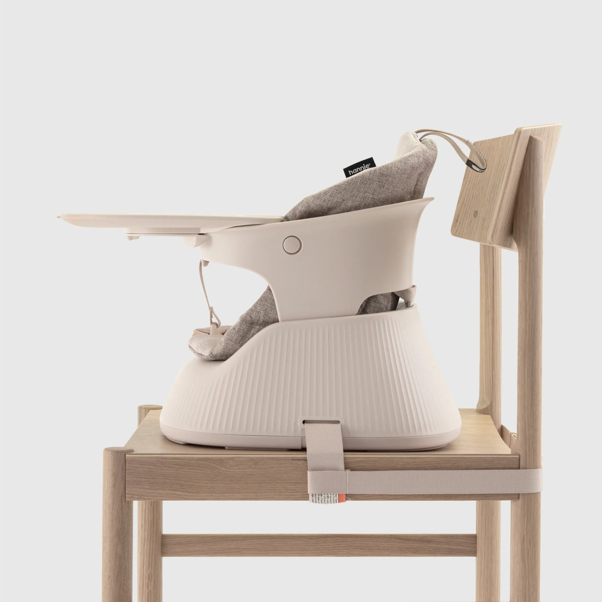 Hannie portable high chair in white sand color, shown from the side view, designed for easy seating and convenience for infants.
